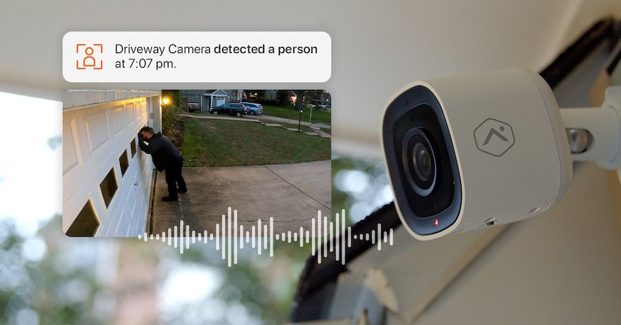 An image and phone notification of a person peering into a garage door overlaid over an image of a security camera.