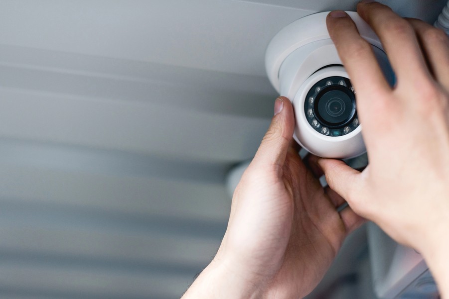 A person holding a security camera for installation. 